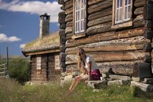 Relaxing in front of a wooden cabin by CH, Visit Norway