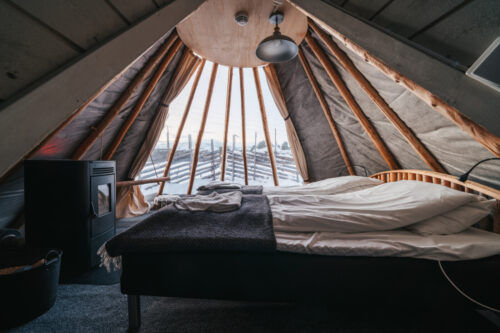 Bed and glass wall inside a tipi by Holmen Husky Lodge
